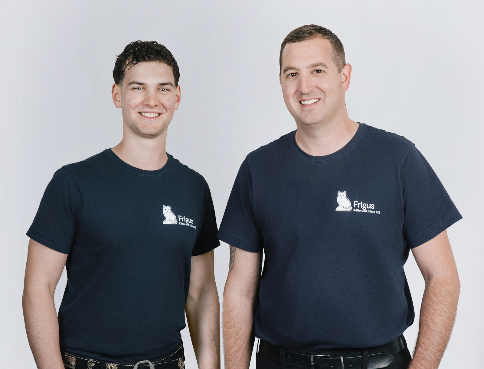 Zwei Mitarbeiter von Frigus in dunklen Firmen-Shirts mit Fuchs-Logo